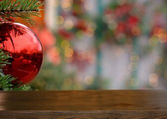 Empty wooden table on the background of a Christmas branch with red ball and golden bokeh. Christmas background.Ready for product montage. Merry Christmas and Happy New Year! Mockup. Copy space.