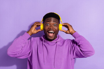 Wall Mural - Portrait of astonished handsome person arms touch headphones have fun isolated on violet color background