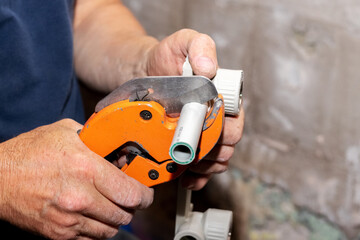 Wall Mural - A plumber uses a special scissors to cut a polypropylene pipe during the installation of a water pipe