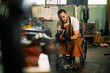© Astarot - A craftsman in a wheelchair is using grinder in his workshop.