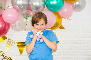 Wall Mural -  happy boy holding colorful easter eggs, standing at home in front of balloons