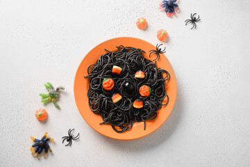 Wall Mural - Halloween alternative creative Italian black pasta squid ink decorated funny candy in orange plate on white background. View from above. Food concept.