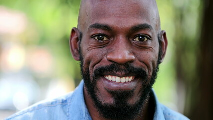 Wall Mural - African man smiling standing outside. Black person portrait face close-up