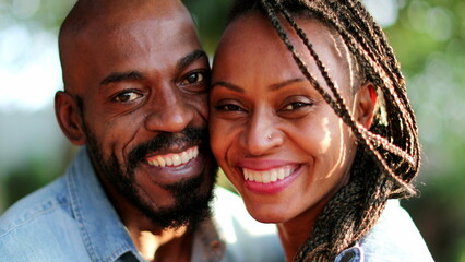 african couple kissing outside, two people smiling at camera