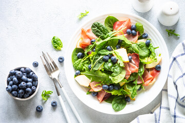 Canvas Print - Healthy salad with spinach, jamon, pear and blueberry. Top view on white background with space for text.