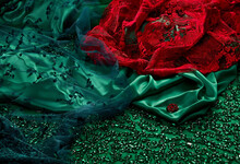 Top View On A Natural Luxury Green Silk Fabric With Rhinestones Embroidery And Red Luxurious Lacey Fine Fabric
