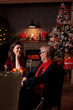 © DC Studio - Daughter talking with mom at christmas festive dinner, family having conversation. Xmas celebration in beautiful decorated place with warm evening candle light, fir tree, garlands on background