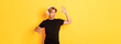 © Mix and Match Studio - Happy attractive asian guy with blond hair, singing along and dancing as listening to music in wireless headphones, standing yellow background