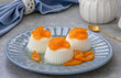 Vanilla panna cotta or jelly custard pudding served on a plate with slices of caramelised tangerines in orange syrup