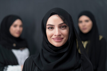 Wall Mural - Group portrait of beautiful Muslim women in a fashionable dress with hijab isolated on black background