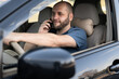 © Andrii Lysenko - Portrait of smiling adult man driving car speaking on cellphone.