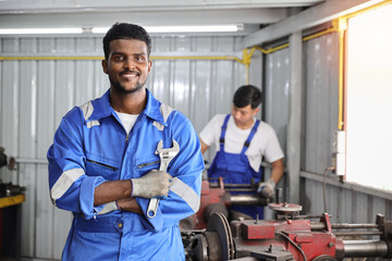 Technicain mechanic crossed arms with wrench and confident while working on metal lathe machine operate polishing car disc brake at garage. Maintenance automotive and inspecting vehicle part concept