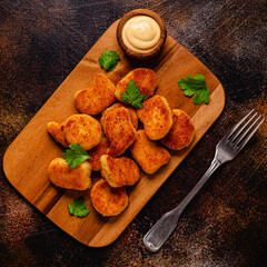 Wall Mural - Fried crispy chicken nuggets on a wooden serving board.