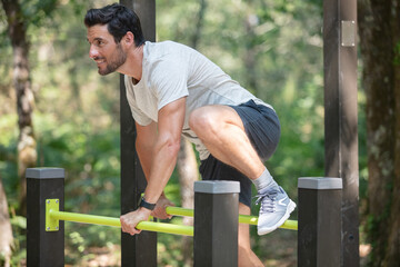 young man jumping on horizontal bar outdoors