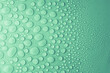Water drops on light mint or turquoise, green background as fresh trendy color pattern with different and gradient droplets, top view.