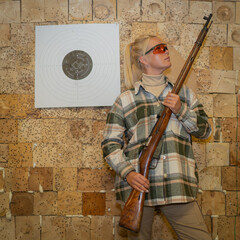 Wall Mural - Young woman with old rifle in shooting range 