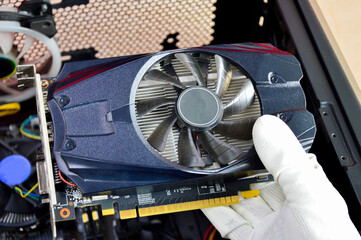 Poster - top view of graphics card Technician about to install, black graphics card in hand.