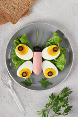 Butterfly made of eggs, sausage, olives and green lettuce leaves - healthy breakfast idea for kids