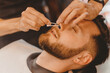 © Parilov - Master barber removes hair from nose of man with wax, depilation beauty procedure