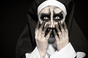 Wall Mural - Portrait of scary devilish nun on black background. Halloween party look