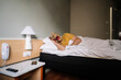 © karrastock - Man with lizard mask in a hotel bed.