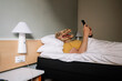 © karrastock - Man with lizard mask using the smartphone in a hotel bed.