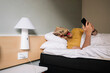 © karrastock - Man with lizard mask using the smartphone in a hotel bed.