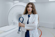 © makedonski2015 - A doctor in a white coat on the background of an MRI. A young woman holds a stethoscope in her hands.