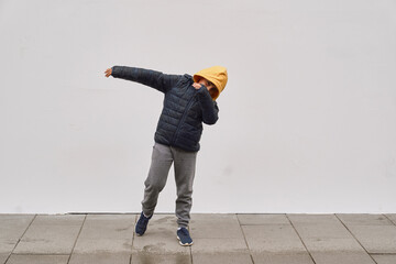 Wall Mural - Little fashionable boy posing in front of white concrete wall. Concept of style and fashion for children