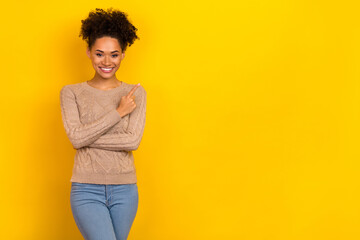 Photo of sweet shiny woman wear beige sweater pointing empty space isolated yellow color background