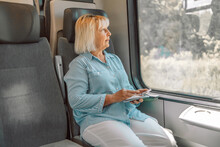 Blonde Caucasian Senior Woman Using Transport Application On Smartphone While Travelling By High Speed Train