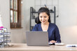 © David - Young Asian female freelancer employee working with laptop at home and papers on desk workplace