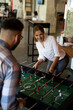 © JustLife - Colleagues having fun at work. Businessman and businesswoman playing table soccer.