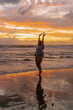 © Yuliya Kirayonak - Happy woman dancing at sunset on the ocean, yellow light.