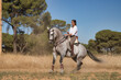 Beautiful young woman performing cowboy dressage exercises, riding her horse in the countryside on a sunny day. Concept horse riding, animals, dressage, horsewoman.