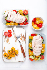 Wall Mural - Healthy meal prep for lunch, diet boiled chicken fillet with vegetables salad in lunch boxes containers top view on white marble kitchen table background with knife and cutting board. Space for text