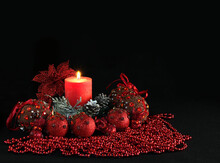 Big Red Lighting Candle,  Red Christmas Tree Decorations With Jewellery, Pine Cones, Baubles And Red Jewellery On A Dark Background 