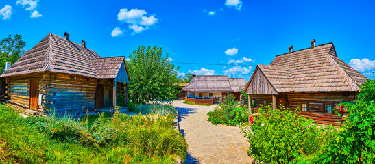 Poster - Panorama of the courtyard of Small Kish of Zaporizhian Sich scansen with timber houses and blooming garden, Zaporizhzhia, Ukraine