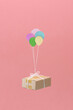© Marc Tran/Stocksy - delivery box flying on air balloon isolated on pink background