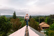 © ByLorena/Stocksy - Woman on top of roof holding security harness