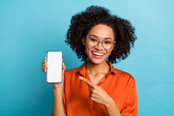 Wall Mural - Portrait of attractive trendy cheery wavy-haired girl demonstrating gadget copy space isolated over bright blue color background