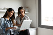 © Valentina Barreto/Stocksy - Mixed businesswomen watching laptop in office kitchen