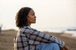 © Jovo Jovanovic/Stocksy - Woman in long sleeves sitting alone at beach