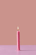 © Yaroslav Danylchenko/Stocksy - Burning pink candle on pastel background.