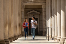 Two Friends University Students Walk In Campus Hallway Outdoors 