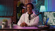 © DC Studio - African american online radio host reading fan mail from laptop talking using microphone in home studio. Social media content creator answering questions from listeners while recording podcast.