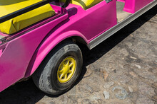 A Pink Golf Cart With Yellow Tires And Seats