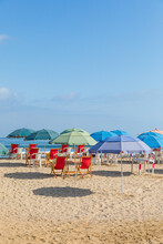 Colorful Umbrellas And Red Chairs On The Sand In A Beach