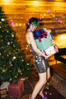 © BONNINSTUDIO/Stocksy - Trendy lady holding gifts and smiling during Xmas party