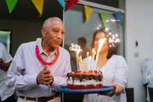Old Man Blowing The Candles Of His Birthday Cake